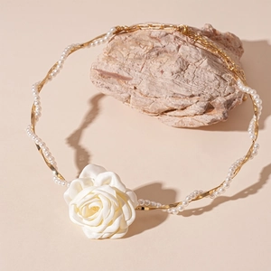 Elegant white fabric rose necklace with gold chain and faux pearls on a stone base