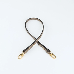 Detail of grey lychee leather handbag strap with gold metal hooks and rivet accents