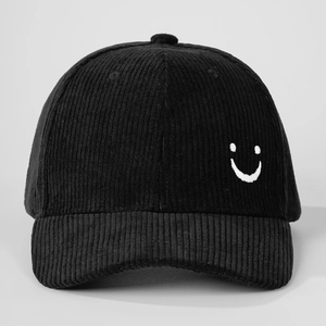 Detail shot of the side white smiley face embroidery on a black corduroy baseball cap