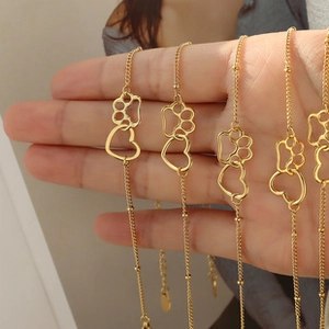 Close-up of 18k gold necklaces featuring openwork cat paw and heart pendants with small beads