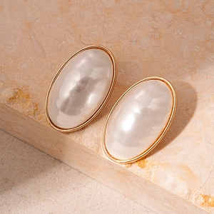Close-up of vintage oval pearl earrings with gold plating on a natural stone base