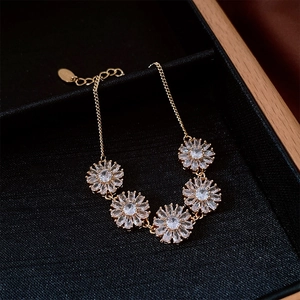 Détail d'un bracelet plaqué or 18 carats avec breloques marguerites et pierres zircon