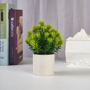 Close-up of artificial green plant in a white ceramic pot for home office decor