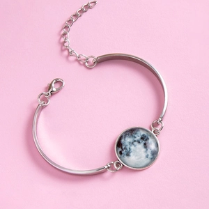 Detailed close-up of a silver lobster clasp and moon pendant on a pink background