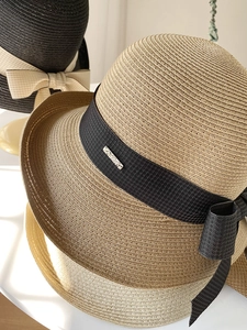 Détail de chapeaux de paille tissés main avec d'élégants nœuds en ruban noir et beige