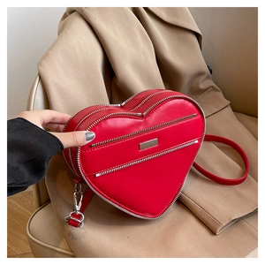 Detail of red heart-shaped leather crossbody bag featuring triple silver zippers