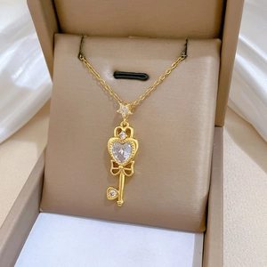 Close-up of golden bow key pendant necklace with sparkling zircons on silk cushion