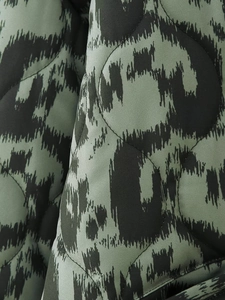 Macro shot of circular quilted fabric with abstract green and black leopard print