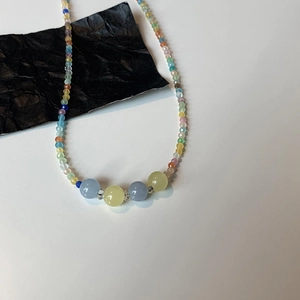 Detailed view of rainbow beaded necklace with colorful stones and blue yellow round beads