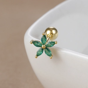Macro shot of 18K gold plated flower stud earring with green zircon on white ceramic