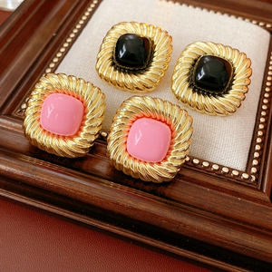 Nahaufnahme von quadratischen Vintage-Ohrsteckern mit Goldrand in Schwarz und Rosa