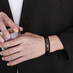 Détail d'un bracelet multicouche en cuir tressé noir pour homme avec fermoir magnétique doré