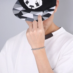 Detailed view of a slim silver square box chain bracelet worn by a male model