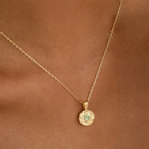 Gold stainless steel coin necklace with irregular texture and green birthstone on a model