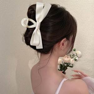 Detail of a large white satin bow hair claw clip styled in an elegant French updo