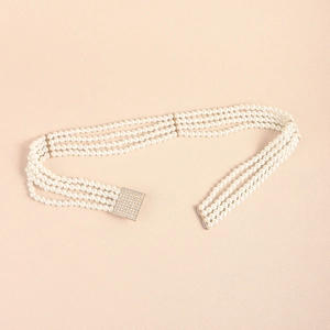 Detailed view of four-row pearl belt with square gold buckle encrusted with crystals