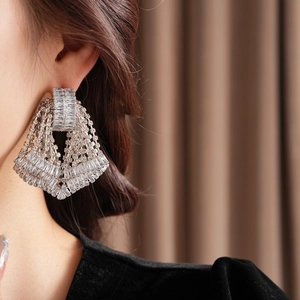 Close-up of geometric silver tassel earrings with crystals on a female model