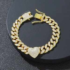 Dettaglio del bracciale a catena cubana dorata con ciondolo a cuore e strass lucidi