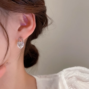 Close-up of asymmetric bear heart lock earrings with cubic zirconia on a model's ear