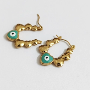 Golden stainless steel heart earrings with turquoise evil eye pendants on white backdrop