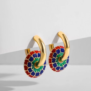 Makroaufnahme von Goldohrringen mit lebendigen rot-blauen Emaille-Blumenanhängern