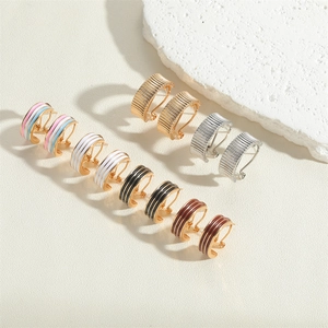 Detail of diverse C-shape earrings featuring striped 14K gold plating and enamel designs