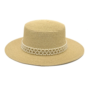 Detail of hand-woven flat top straw hat with three rows of elegant white pearl trim