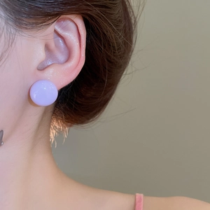 Close-up of a minimalist round lavender purple stud earring worn on the earlobe