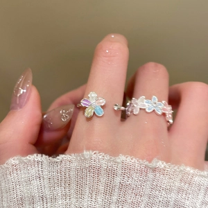 Close-up of zircon flower rings with colorful enamel on a model's hand wearing white knitwear