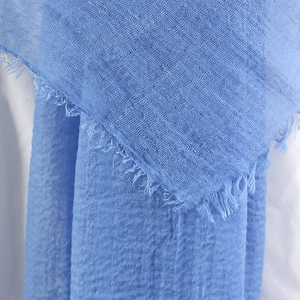 Detailed macro view of the blue cotton linen scarf texture with soft fringe edges