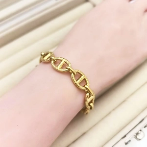 Detailed view of golden pig nose link bracelet with textured finish on model wrist