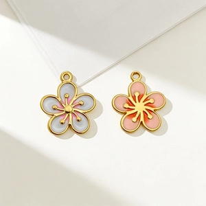 Detailed macro view of two gold-plated stainless steel flower pendants in pink and white