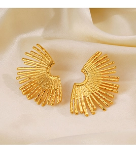 Macro detail of gold-plated fan-shaped earrings with radial lines on beige silk