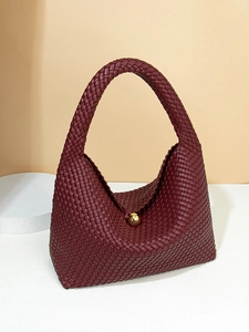 Reddish brown hand-woven crescent bag with golden sphere clasp and leather texture