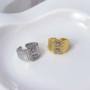 Detailed close-up of gold and silver open rings with honeycomb texture and double square stones