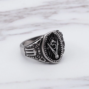 Close-up of vintage stainless steel Freemason skull ring on white marble surface