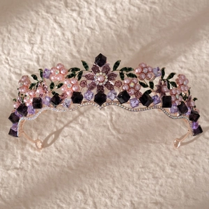 Detailed view of rose gold bridal crown with purple crystals and green enamel leaves