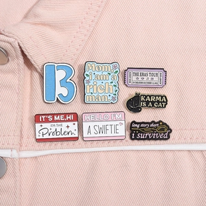 Close-up of six colorful Taylor Swift themed enamel pins on a pink denim jacket