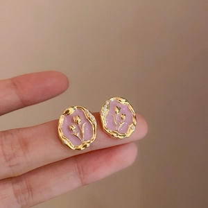 Dettaglio di orecchini a tulipano rosa con rilievo dorato e bordo in perle