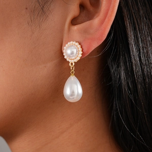 Detail view of pearl drop earring with golden base and small pearls on model ear