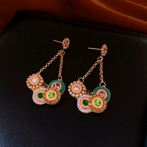 Close-up of vintage gold tassel earrings with colorful crystal circles on black leather