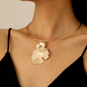 Close-up of golden fan-shaped metal pendant and textured ginkgo leaf choker necklace