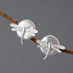 Creative S925 silver dragonfly stud earrings with white pearls on a natural wood branch