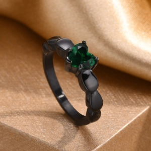 Macro detail of heart-shaped green gemstone set on a unique black drop-style ring band