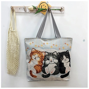 Detail of jacquard tote bag featuring three cute cats illustration and striped handles