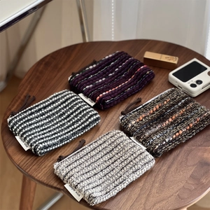 Detailed view of woven mini coin purses in four patterns on a wooden table with accessories