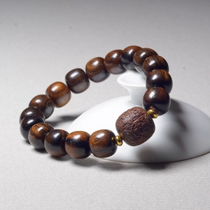 Close-up of eaglewood beads with a detailed engraved centerpiece and golden spacers