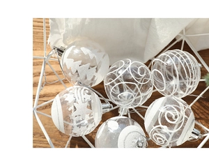 Close-up of clear Christmas ornaments with white snow patterns in a metal basket