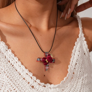 Close-up of a creative plaid fabric cross pendant with velvet bear detail and metal charm