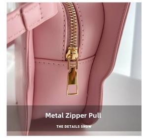 Close-up of premium gold-toned zipper hardware on a soft pink leather crossbody bag